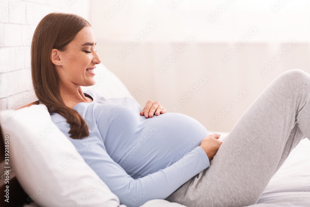 Pregnant Lady Touching Belly Lying In Bed, Side View Pregnant Lady Touching Belly Lying In Bed, Side View