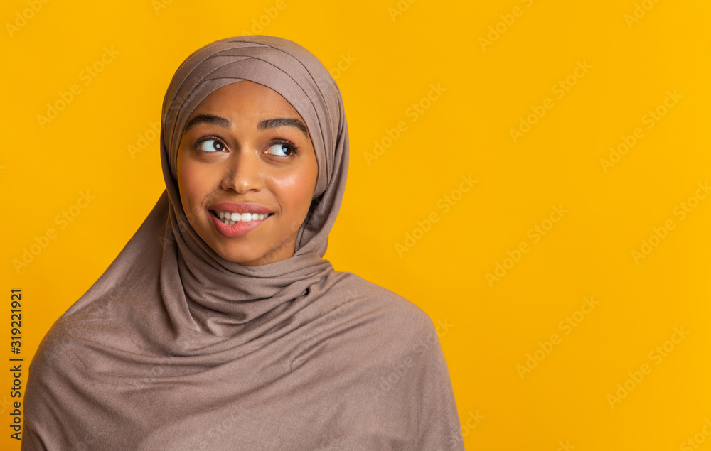 Doubtful black muslim woman in headscarf biting lip and looking aside Doubtful black muslim woman in headscarf biting lip and looking aside