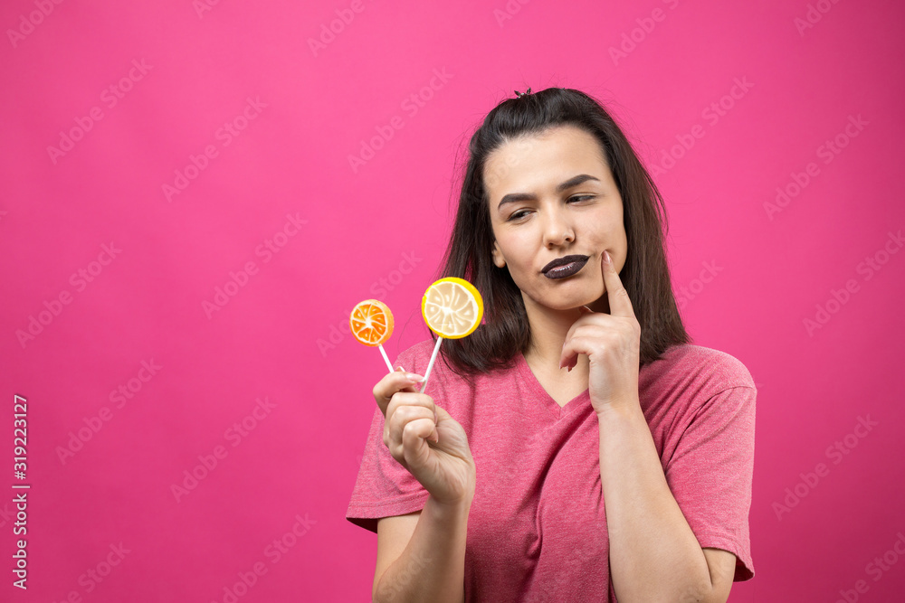 Portrait of lovely sweet beautiful cheerful woman with straight brown hair holding a lollipop near the eyes. Portrait of lovely sweet beautiful cheerful woman with straight brown hair holding a lollipop near the eyes.