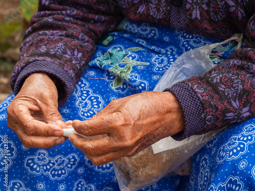 Hand of aged woman rolling tobacco, countryside rural lifestyle.
