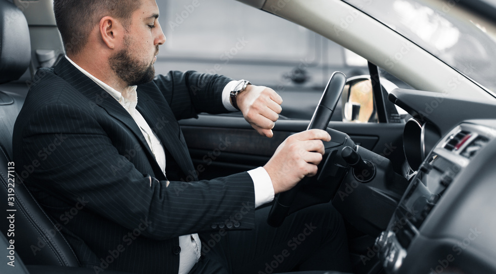 Handsome caucasian businessman driver inside in vehicle with coffee and gadget and check mail and talking with partners Handsome caucasian businessman driver inside in vehicle with coffee and gadget and check mail and talking with partners