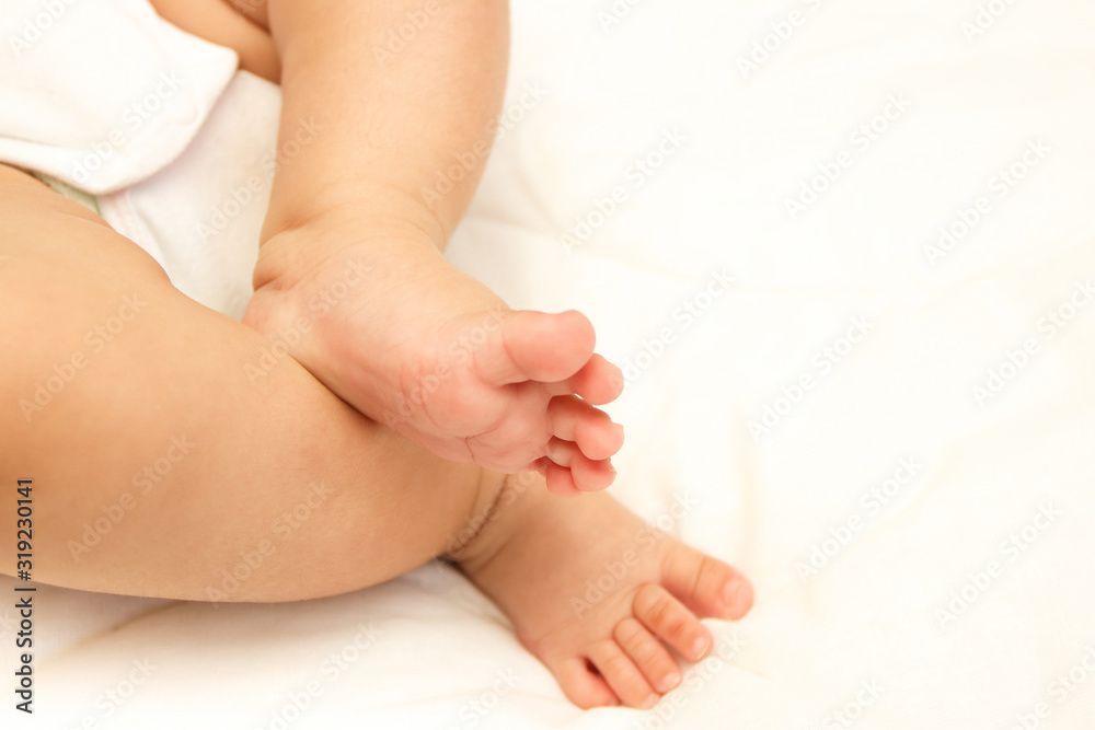 Legs of infant on the white blanket, bedroom, blurred background Legs of infant on the white blanket, bedroom, blurred background