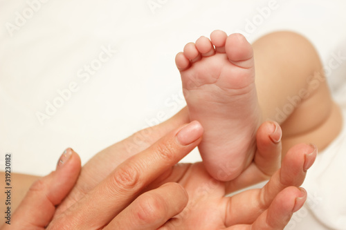 Hands of woman holds baby foot, blurred background