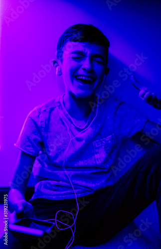 A young boy listening to music in his bedroom with LED lights on.