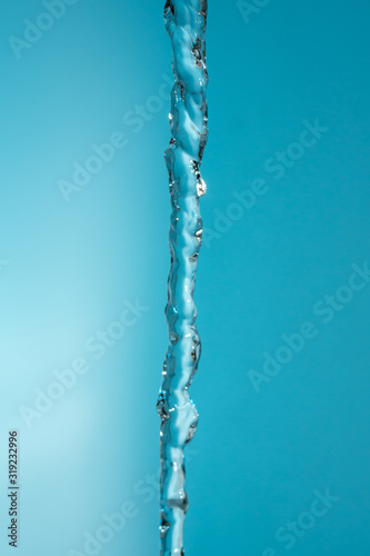 water stream pouring down on blue background copy space close up