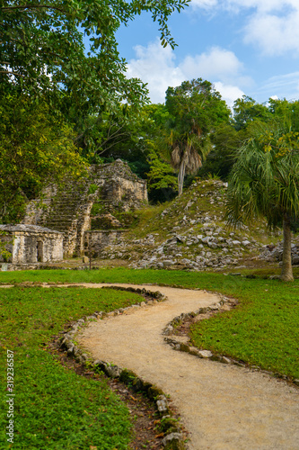 Ruins of ancient Muyil. Architecture of ancient maya. View with temple and other old buildings, houses. Blue sky and lush greenery of nature. travel photo. Wallpaper or background. Yucatan. Mexico.