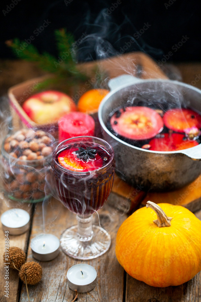 Christmas red wine mulled wine with spices and fruits on a wooden rustic table. Traditional hot drink for Christmas. Mulled wine hot drink with citrus fruits, apples and spices in a pan. Hot drink