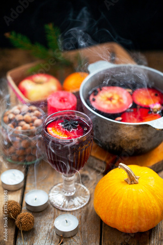 Christmas red wine mulled wine with spices and fruits on a wooden rustic table. Traditional hot drink for Christmas. Mulled wine hot drink with citrus fruits  apples and spices in a pan. Hot drink