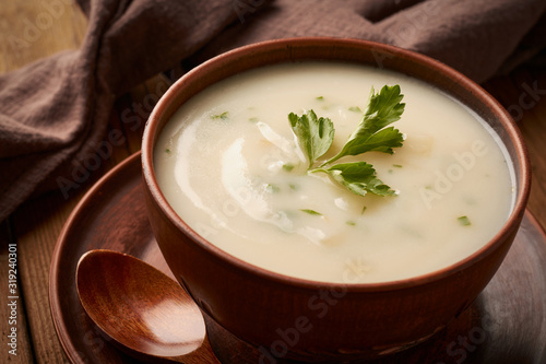 Bowl of potato soup with parsley on a wooden background