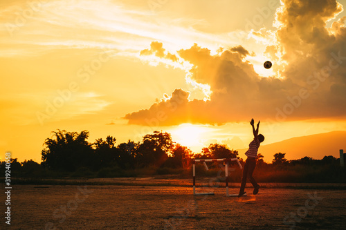 Silhouette action sport outdoors of kids having fun playing soccer football for exercise in community rural area under the twilight sunset. Picture with copy space.