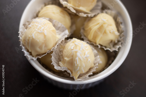 Homemade white chocolate truffles with coconut filling and whole almond. Raffaello balls with condensed milk. Close-up shot, selective focus.