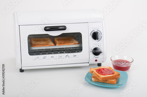 Household kitchen utensils; Small white toaster oven.