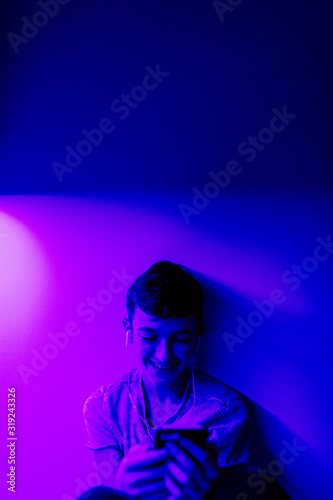 A young boy listening to music in his bedroom with LED lights on.