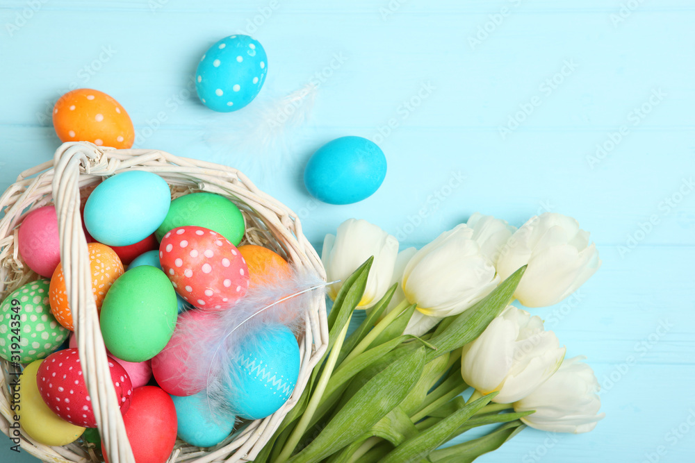 Fototapeta premium Easter eggs and flowers on the table top view. Easter composition with a place to insert text.