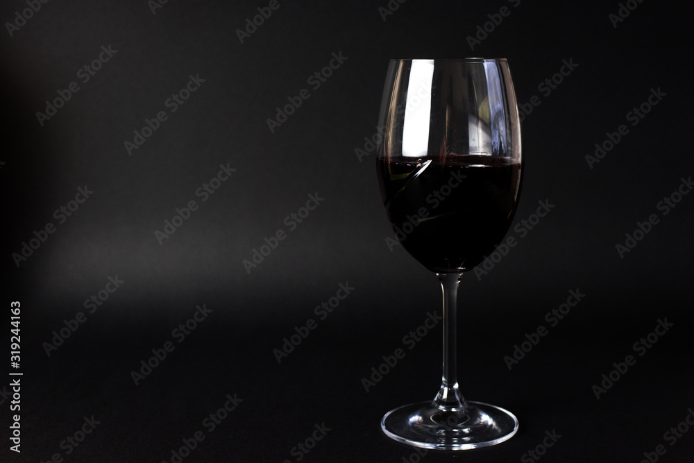 A glass with red wine on the black backround