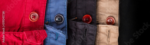 Banner of fagment of four cotton twill pants red, blue, black, beige with open buttons. photo