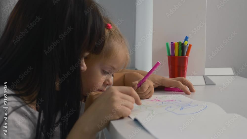 Happy family. Mom and daughter draw a picture in the album. Home schooling. Doing homework. Teamwork Happy family. Mom and daughter draw a picture in the album. Home schooling. Doing homework. Teamwork