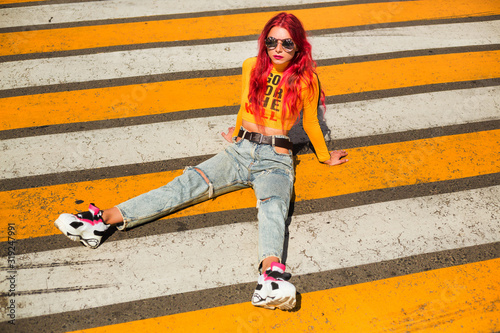 Bright exciting girl with red hair, 90s, 2000s style, T-shirt, wide jeans, bananas, sneakers. Sitting at a pedestrian crossing