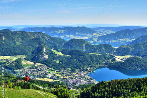 Zwolferhorn, green mountains and fields in Austria, trees and lakes, a bird's-eye view of the city, in the spring afternoon.