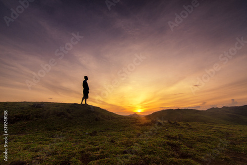 silhouette of man on top of mountain at sunset