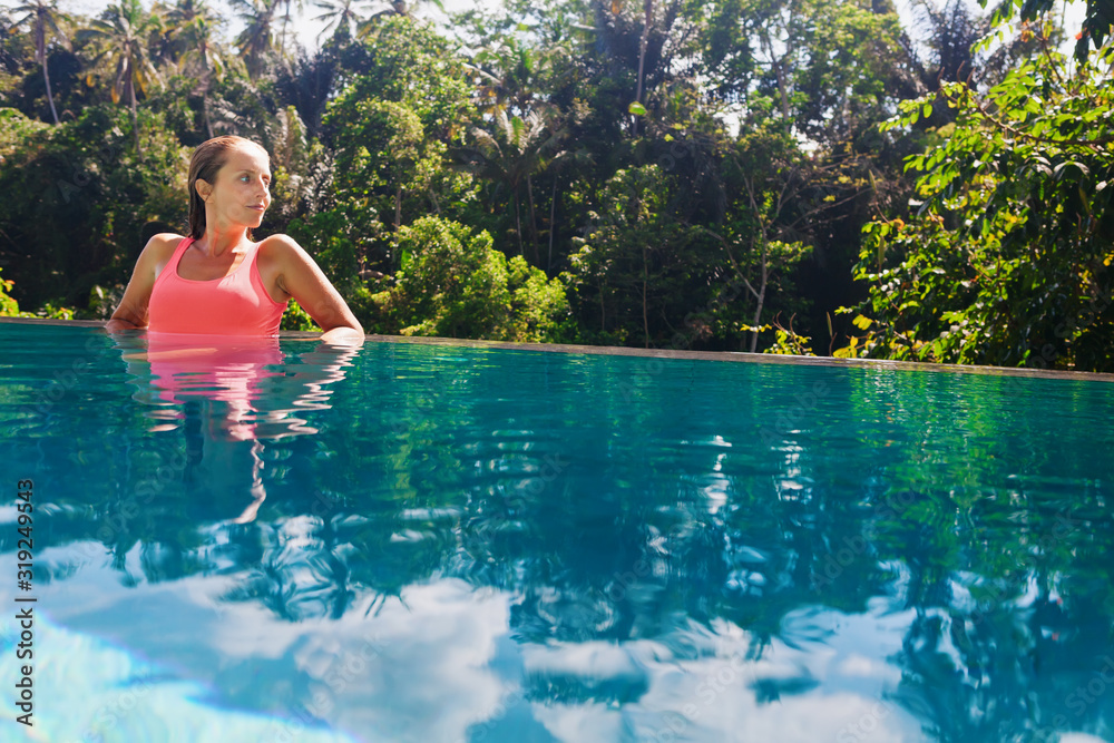 Fototapeta premium Woman relaxing in luxury spa hotel in infinity swimming pool