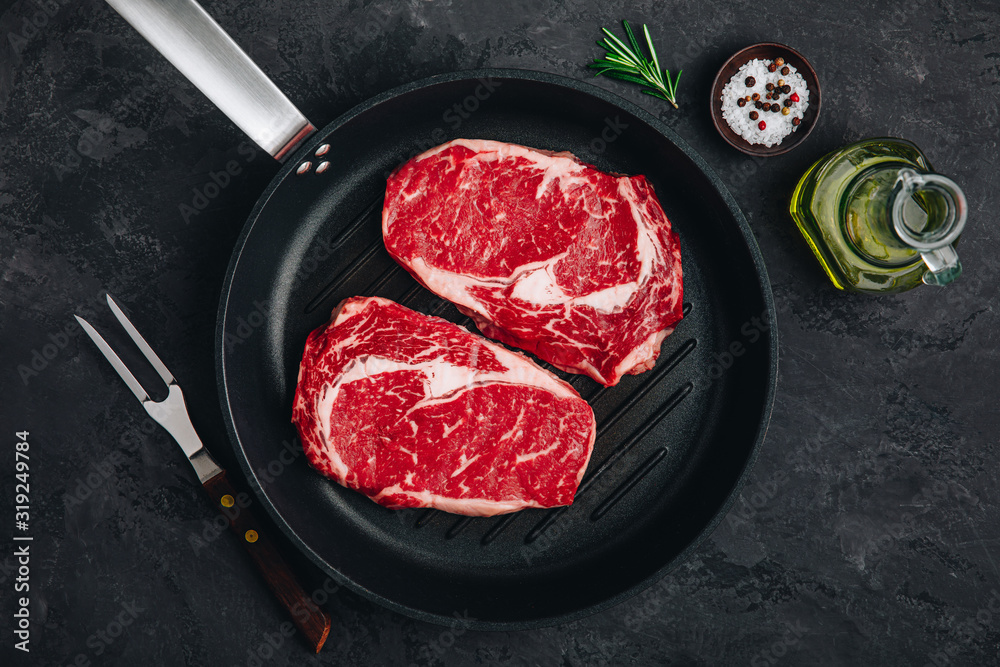 Ribeye Steak, Raw fresh beef meat with salt and rosemary in grill pan Ribeye Steak, Raw fresh beef meat with salt and rosemary in grill pan