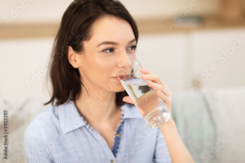 Smiling girl drinking clean water from glass