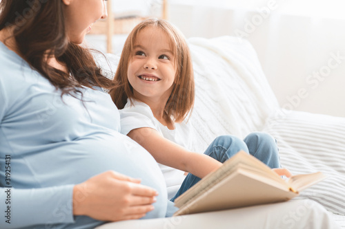 Close up of little girl looking at mom while reading