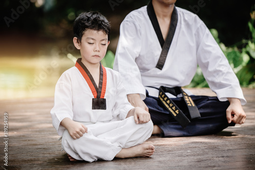 Fighter kid in Taekwondo uniform sitting concentration for training self defense body and mild.