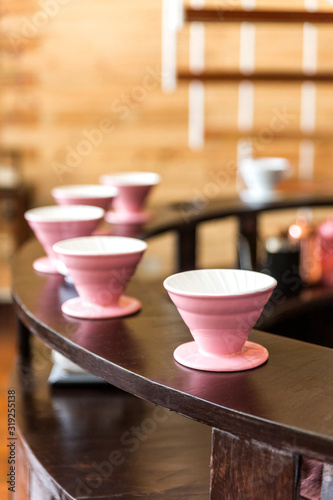 Pink coffee grinder, coffee stand and pour-over on a wooden counter for making pour-over coffee with alternative method called Dripping.