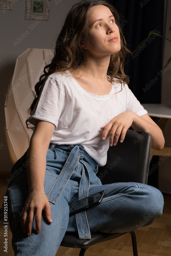 Curly hair girl in casual clothes sitting on chair at home Curly hair girl in casual clothes sitting on chair at home
