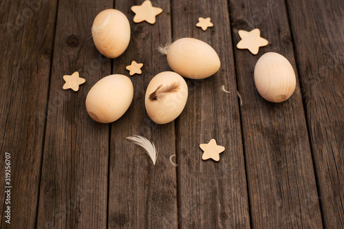 Happy Easter  Wooden eggs  feathers  stars on a wooden background. Minimum concept of Easter. Easter card with a copy of the text space. Top of view  Flatley.