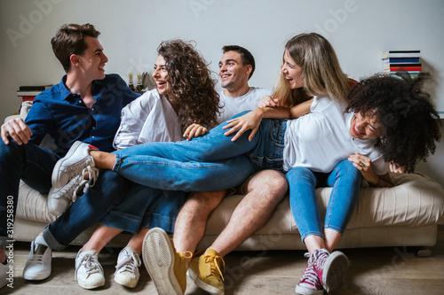 Portrait of a group of friends sitting on the sofa at home - Millennials have fun together in an apartment