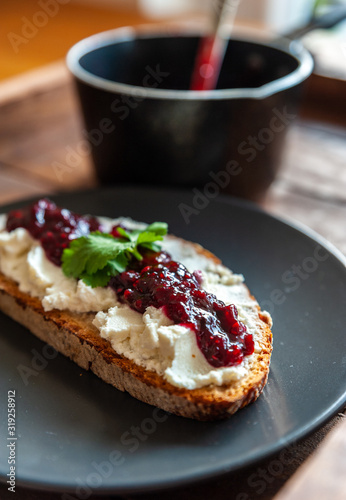 Close up shot of a slice of a bread topped with ricotta cheese and jar