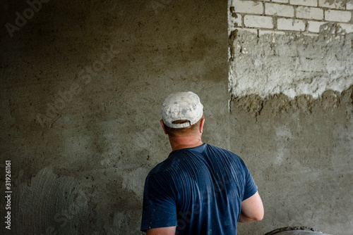 Worker applying plaster on the wall using a trowel.