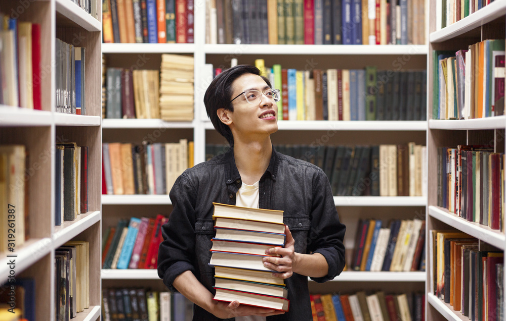 Young chinese man in glasses standing at library Young chinese man in glasses standing at library
