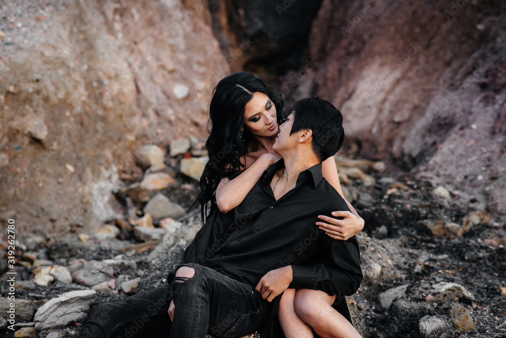 Asian couple in love hugs sitting on the rocks. Love story