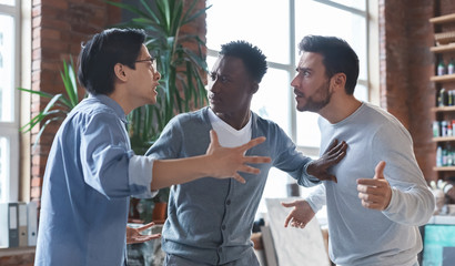 Multiracial coworkers having quarrel in office, conflict of interest