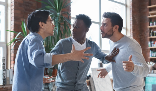 Multiracial coworkers having quarrel in office, conflict of interest