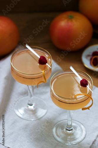 Champagne cocktail with grapefruit juice, garnished with zest and raspberries. Rustic style.