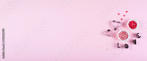 Banner for website design. Valentine's day background. Cooking background with cookie cutters and pink sugar sprinkling on pink background. Flat lay, top view, copy space