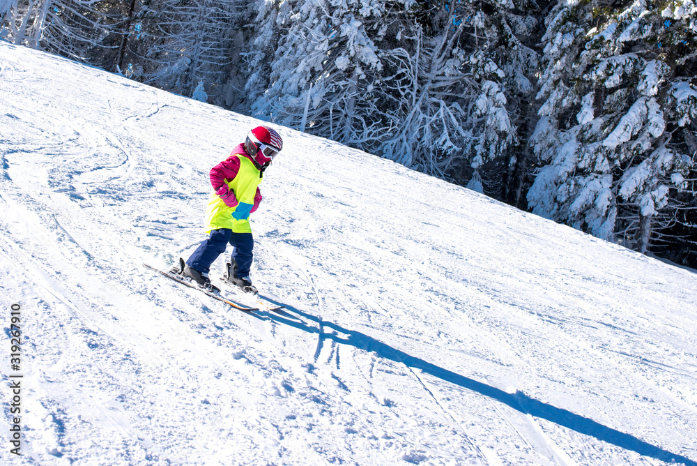 Young skier skiing in mountain ski resort during winter vacation