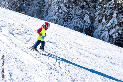 Young skier skiing in mountain ski resort during winter vacation