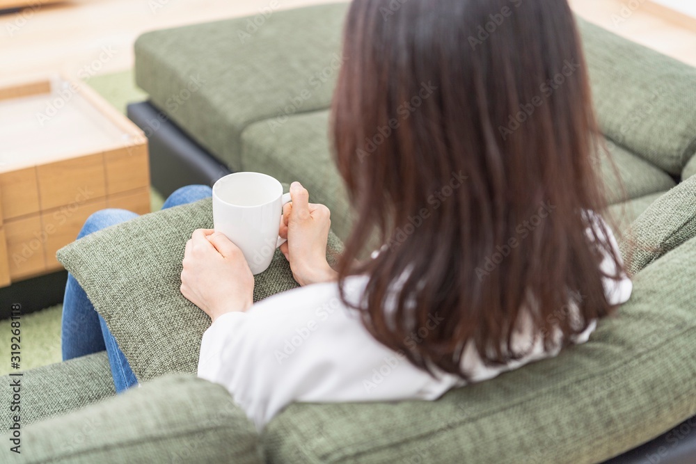 マグカップを持ってソファーに座る女性