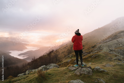 Hiker taking a photo of cloud inversion down in the valley during sunrise