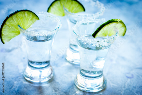 Silver tequila shots with lime and salt on gray stone background