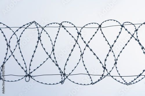 Barbed wire against a white sky.