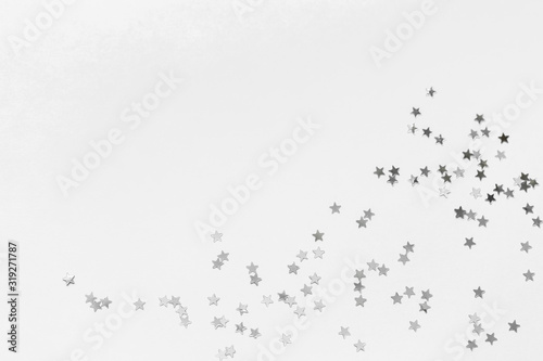 Silver confetti and stars and sparkles on a light background. Top view, flat lay. Copy text. holiday background. For Christmas, New Year, Valentine's Day © Nana_studio