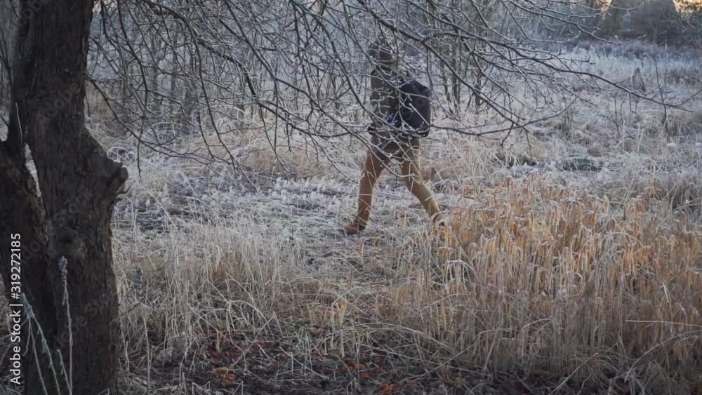 A man walks through a frozen park. Slow motion, smooth camera movement behind the subject. A man walks through a frozen park. Slow motion, smooth camera movement behind the subject.