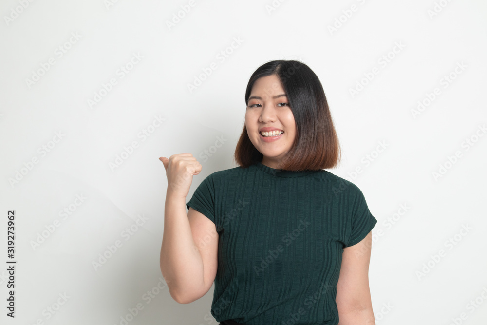 Young Asian woman smile and point to copy space with her thumb Young Asian woman smile and point to copy space with her thumb
